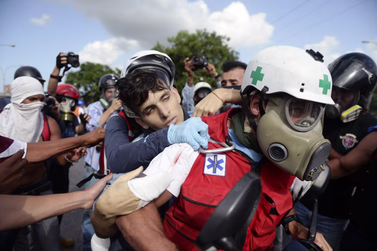 Image: A demonstrator shot by riot police is carried away by medics
