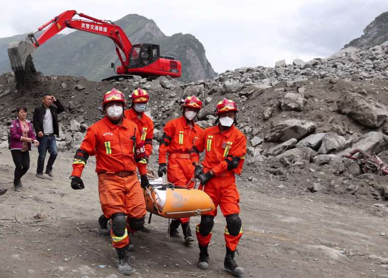 Image: Rescue workers carry a victim out of the rubble on June 25.