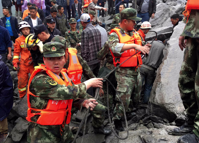 Image: Chinese military police and rescue workers look for victims on June 25.