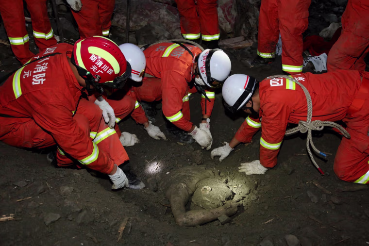 Image: Rescue workers try to remove the body of a victim at the site of the landslide on June 24.