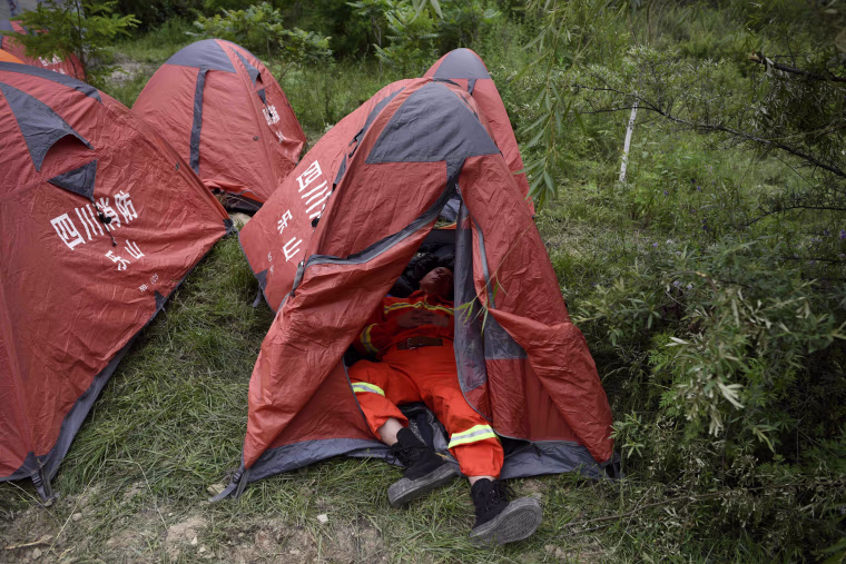 Image: A rescue worker takes a rest in a tent on June 24.