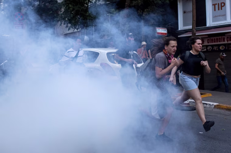 Image: LGBT supporters run from tear gas fired by police after attempting to march to Taksim Square