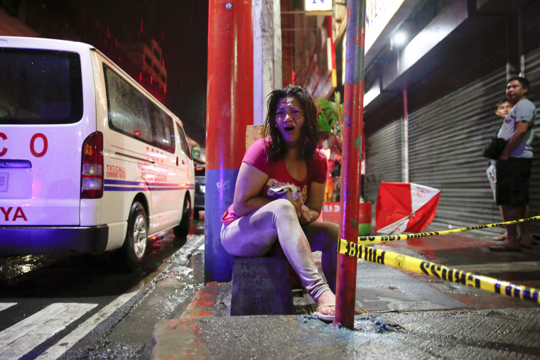 Image: A woman cries after her husband was shot dead by unidentified gunmen riding motorcycles in Manila