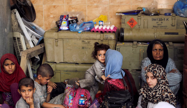 Image: Displaced Iraqi civilians who were rescued from the site of a battle rest among Iraqi forces on June 29.