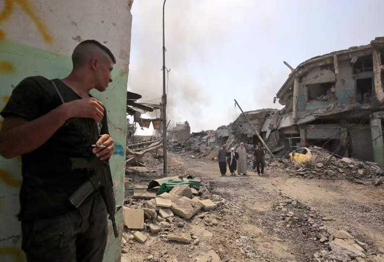 Image: A member of the Iraqi forces smokes a cigarette as he watches Iraqis evacuating from the Old City of Mosul on June 30, during the offensive to retake the city from Islamic State fighters.