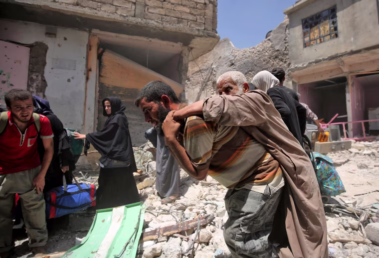Image: An Iraqi carries and elderly man while fleeing Mosul on June 30.