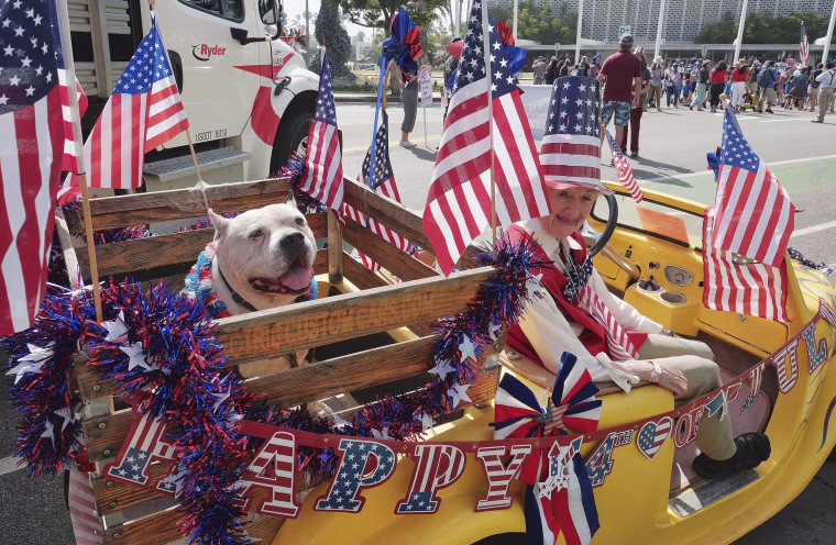 Image: Jasper, a 10-year-old Pit Bull, shares a ride in an electric vehicle with Ellen Brennan during the 4th of July parade