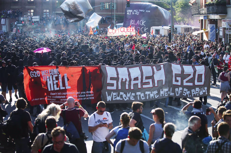 Image: Protesters hold placards as they wait for the demonstration during the G20 summit in Hamburg