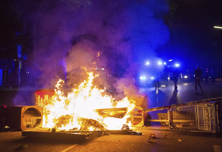 Image: Policemen stand behind a burning barricade in Hamburg.
