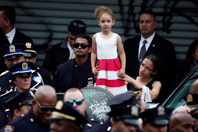 Image: A young girl is lifted above the crowd as police officers gather for the funeral service for slain New York City Police Department (NYPD) officer Miosotis Familia in the Bronx borough of New York City