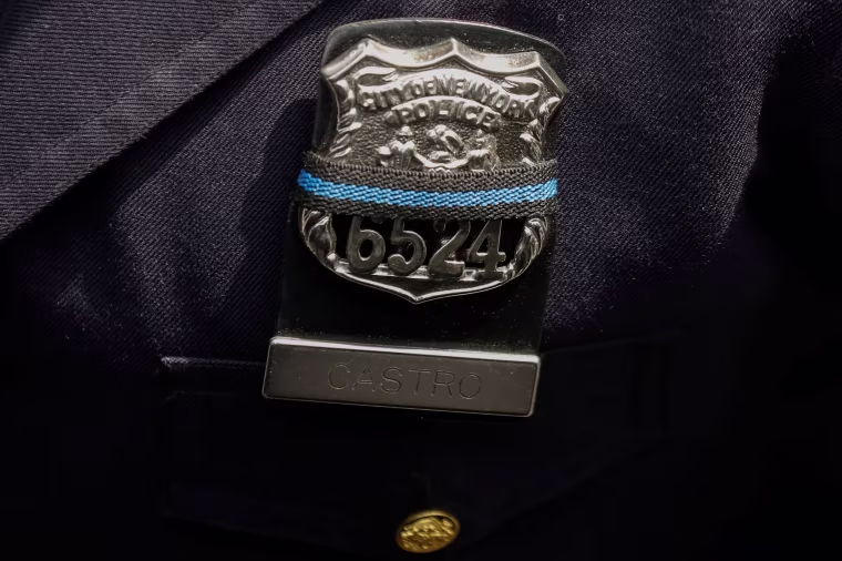 Image: An officer wears an NYPD Police shield covered with a mourning band as officers gather for the funeral service for slain New York City Police Department (NYPD) officer Miosotis Familia in the Bronx borough of New York City