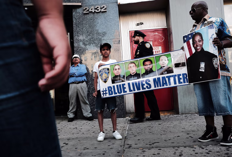 Image: Cameron Hunt stands with his father Calvin holding a Blue lLves Matter banner