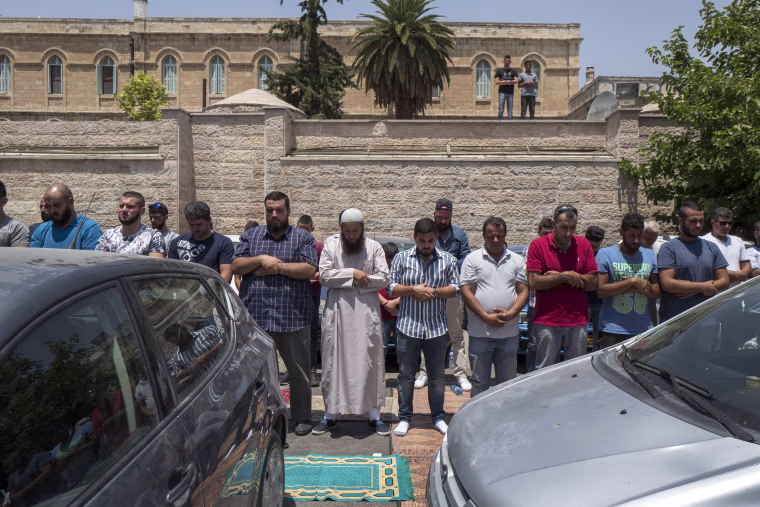 Image: Palestinian Muslims hold prayers in a parking lot