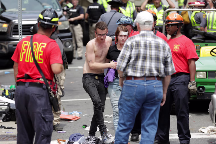 Image: A woman who was injured when a car drove through a group of counter protestors at the \"Unite the Right\" rally is helped in Charlottesville