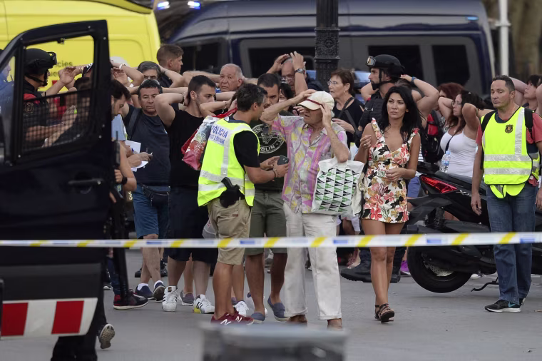 Image: Policemen check the identity of people standing with their hands up after a van struck pedestrians, killing at least 13 people
