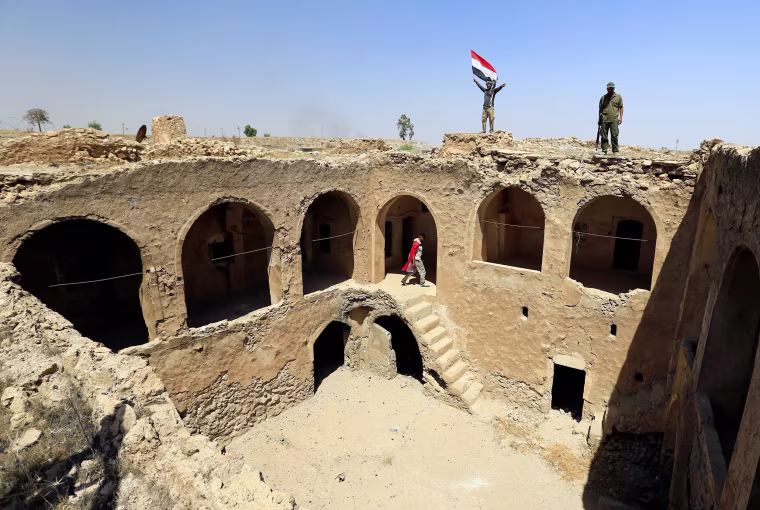 Image: Shiite Popular Mobilization Forces (PMF) members carry an Iraqi flag on the top of Tal Afar castle after it was liberated from Islamic State militants