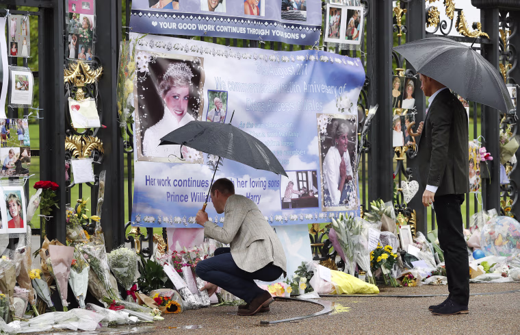 Image: Britain's Prince William, right, and Prince Harry look at floral and pictorial tributes to their late mother Princess Diana placed on the gates of Kensington Palace, London