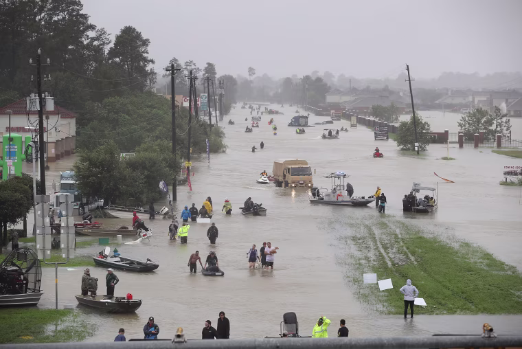 Image: People walk down a flooded street as they evacuate their homes from flooding caused by Hurricane Harvey