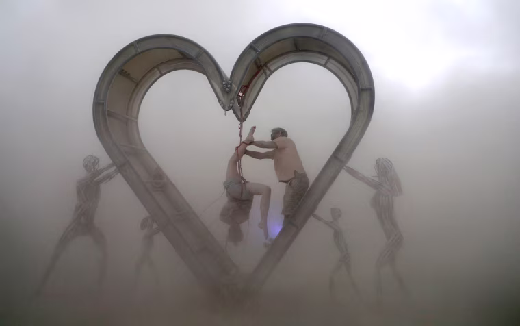 Image: Burning Man participants perform a shibari rope scene during desert dust storm at the Burning Man festival in the Black Rock Desert of Nevada