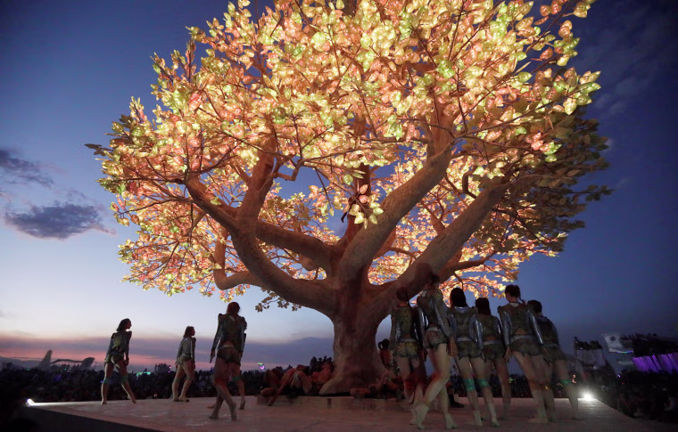 Image: Burning Man participants give a dance performance as the \"Playa Players Collective\" orchestra play Stravinsky's \"Rites of Spring\" in front of a huge art project in the middle of the open desert during the 2017 Burning Man festival in the Black Rock