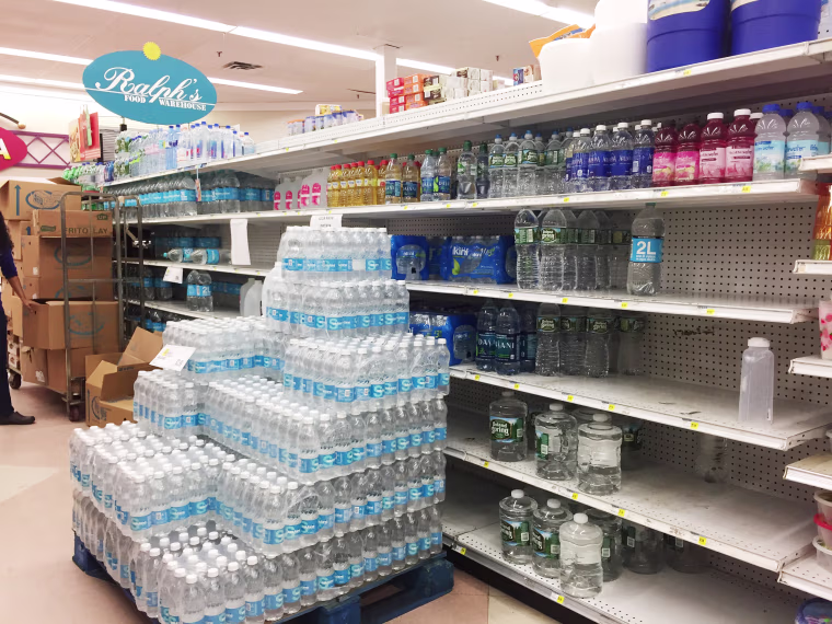 Image: Water bottles have been placed in front of partially empty shelves at Ralph's Supermarket in Gurabo, Costa Rica