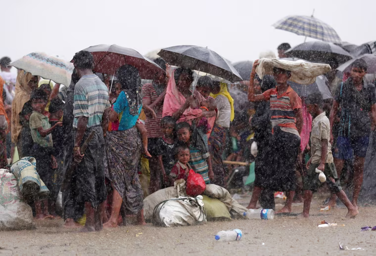 Image: Rohingya refugees stand in an open area during heavy rain as they are held by the Border Guard Bangladesh (BGB) after crossing the border, in Teknaf