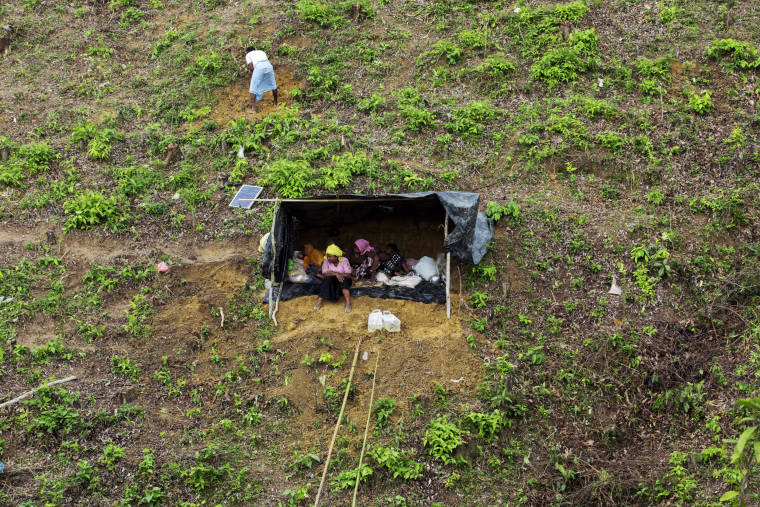 Image: Displaced Rohingya women and children sit in a makeshift shelter in a mountain in Ukhia, as members of the Rohingya Muslim minority fleeing unrest take shelter in a no-man's land