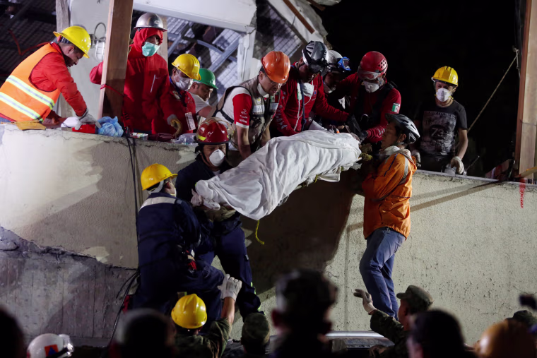 Image: Rescue workers remove a dead body after searching through rubble in Mexico City
