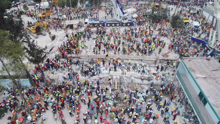 Image: This aerial view shows rescuers, firefighters, policemen, soldiers and volunteers searching for survivors in a flattened building in Mexico City