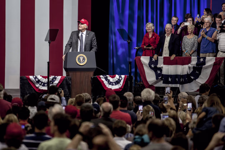 Image: Strange puts on a Make America Great Again hat at in front of supporters at his rally.