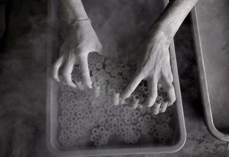 Image: A worker removes paper rolls after filling them with gunpowder mixture to make firecrackers at a factory on the outskirts of Ahmedabad