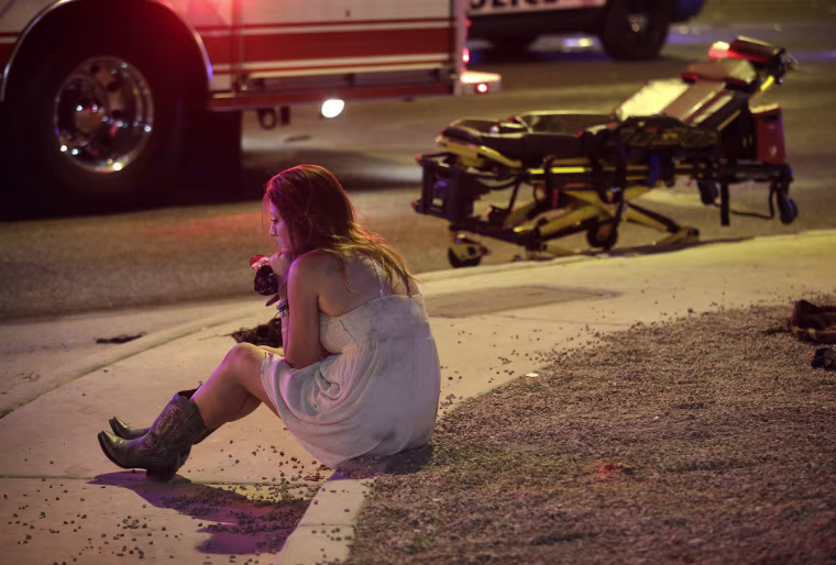 Image: A woman sits on a curb at the scene of a shooting in Las Vegas