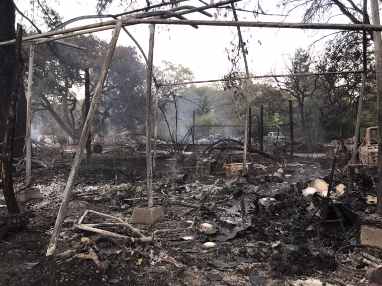 Cars and the remainders of outbuildings smolder on Castle Road in Sonoma.