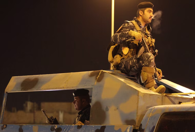 Image: Iraqi police monitor as people gather in the street in the city of Kirkuk