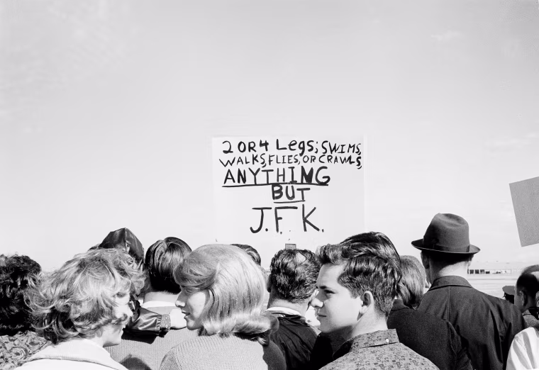 Image: Anti-Kennedy protesters with placards are seen among the throngs of supporters that came out to Love Field in Dallas