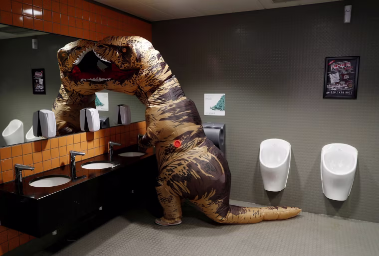 Image: Visitor wearing a T-Rex costume uses the lavatory at the London Comic Con, at the ExCel exhibition centre in east London