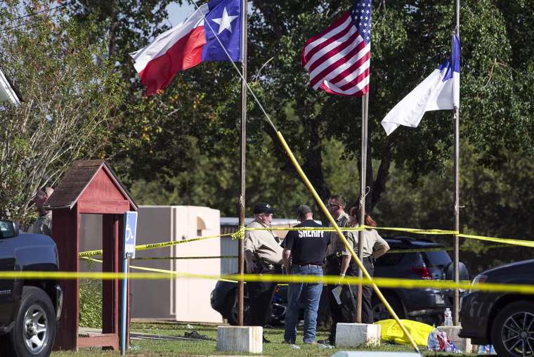 Image: Law enforcement officials stand next to a covered body at the scene of a fatal shooting