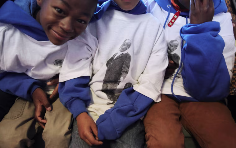 Image: Children wear t-shirts featuring a child who died of AIDS