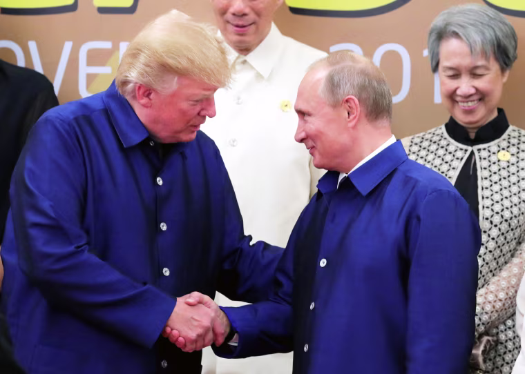 Image: U.S. President Donald Trump and Russian President Vladimir Putin shake hands as they take part in a family photo at the APEC summit in Danang