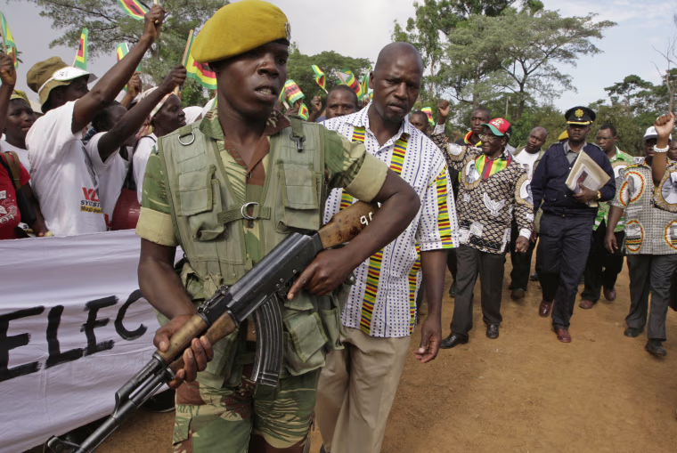 A soldier closely guards Mugabe, in red cap, upon his arrival at a rally in Mubayira, south of Harare, on March, 13, 2008. The country hit rock bottom in 2008, when 500 billion percent inflation drove people to support the challenge of Western-backed former union leader Morgan Tsvangirai. Facing defeat in a presidential run-off, Mugabe resorted to violence, forcing Tsvangirai to withdraw after scores of his supporters were killed by ZANU-PF thugs.