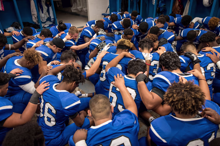 Image: The C.E. King Panthers pray in the locker room before the big game