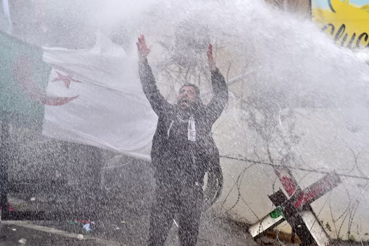 Image: A man shouts as he stands in front of water cannon used by Lebanese riot policemen to disperse protesters during a protest
