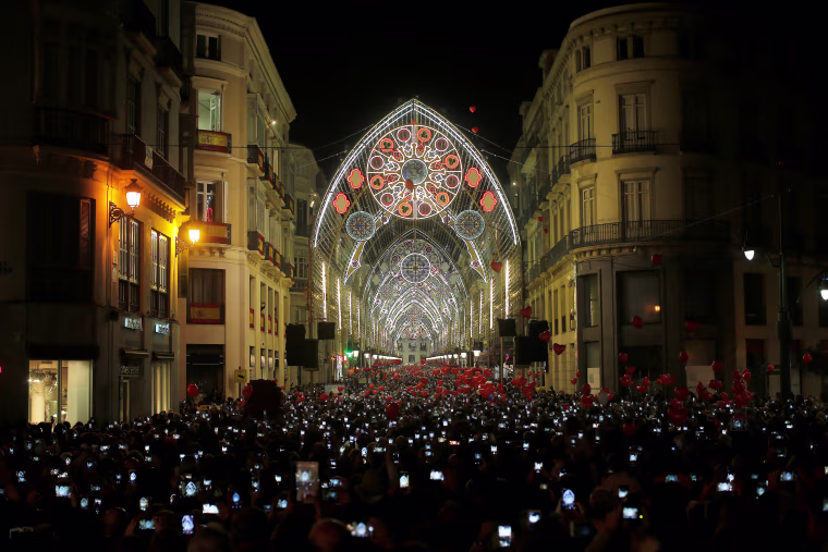 Image: People use mobile phones to take pictures as Christmas lights are turned on to mark the start of the Christmas season in downtown Malaga