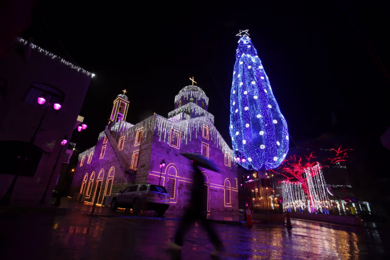 Image: A man walks past Christmas decorations in Maghdouche village near Sidon, Lebanon