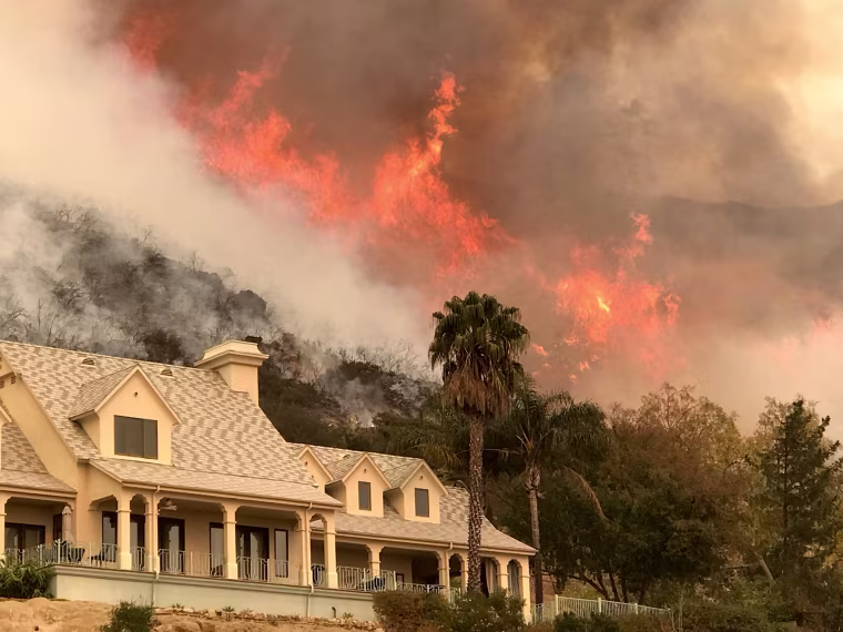Image: Flames from a back firing operation underway rise behind a home off Ladera Ln near Bella Vista Drive in Santa Barbara, California on Dec. 14, 2017.