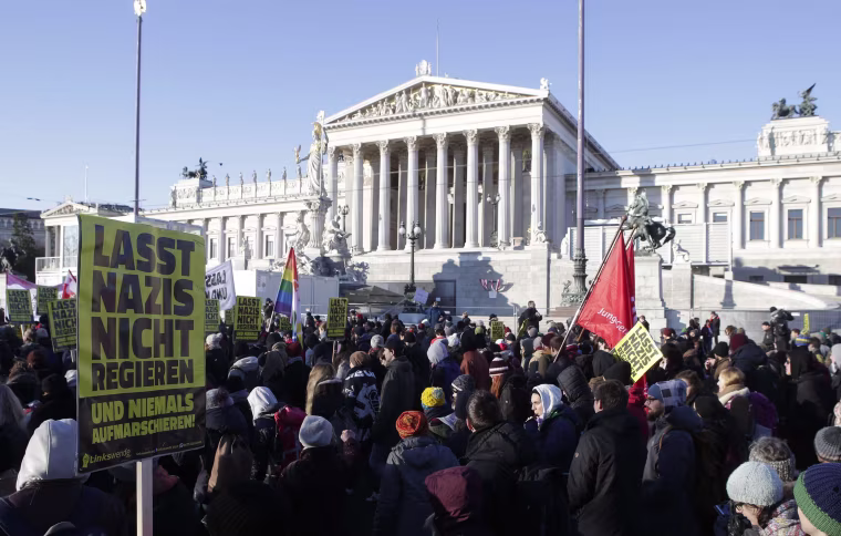 Image: Protesters hold banners in front Austria's parliament 