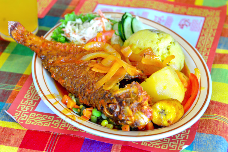 A delicious meal of fish, rice and peas, plantain, macaroni and coleslaw.