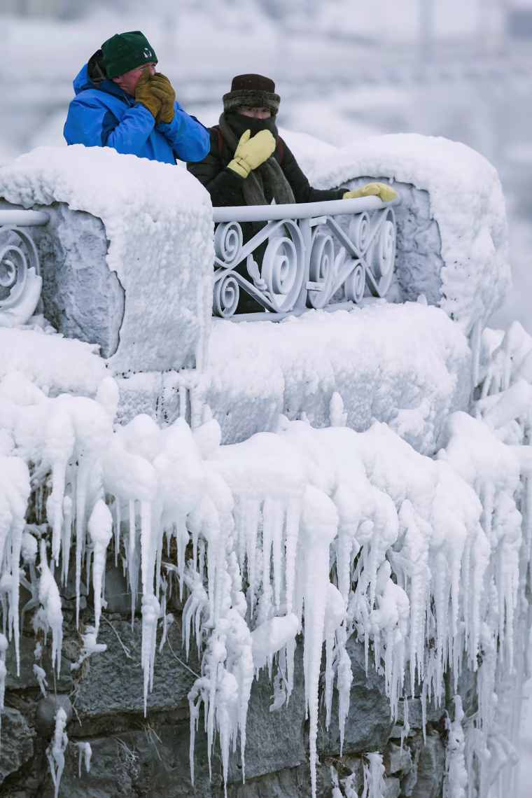 Image: Visitors try to keep warm at the brink of the Horseshoe Falls in Niagara Falls