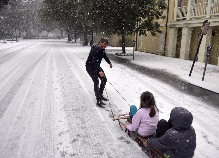 Image: Ramon Martinez takes advantage of little car traffic to pull a sleigh filled with his children Amy and Anthony down Bull Street toward Monterey Square, in Savannah
