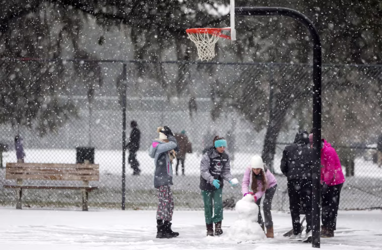 Image: Children from the Hoffman and Lynns families build a snowman on the public basketball courts in Forsyth Park